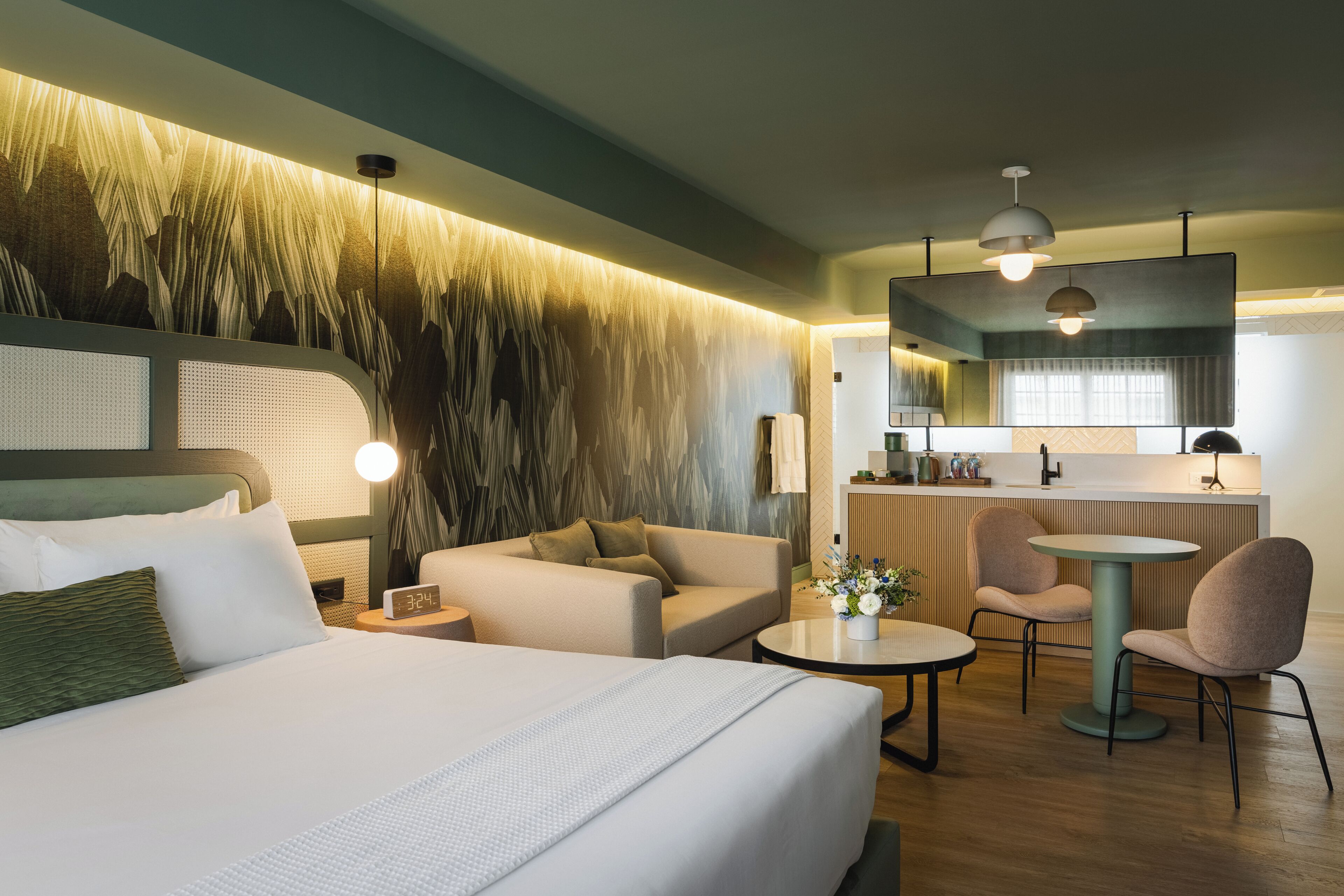 Una habitación de hotel con cama, sofá, una mesita y un rincón de cocina.