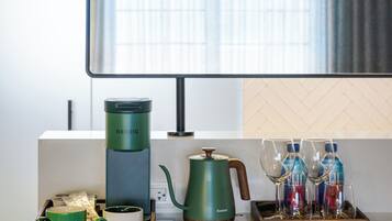 A modern kitchen with a coffee maker, kettle, and glassware on the counter.