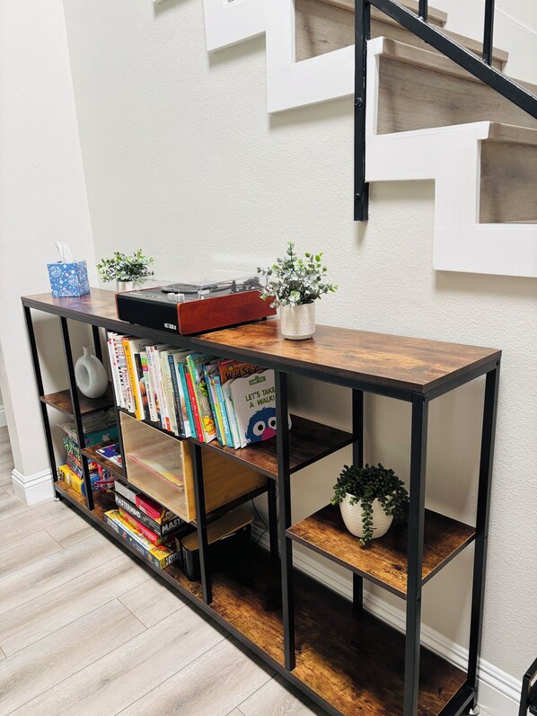 Ein Holzkonsolentisch mit Bücherregalen, einem Plattenspieler und Zierpflanzen.
