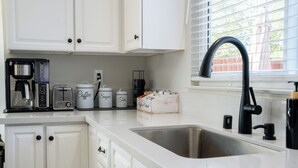A kitchen with white cabinets, a coffee maker, a toaster, and a sink. - Dual Master Rooms - Perfect for Groups & Family-friendly - Fire Pit, BBQ, Games (Moreno Valley)
