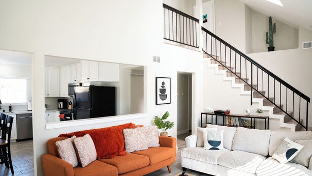A modern living room with a sofa, coffee table, and a staircase. - Dual Master Rooms - Perfect for Groups & Family-friendly - Fire Pit, BBQ, Games (Moreno Valley)