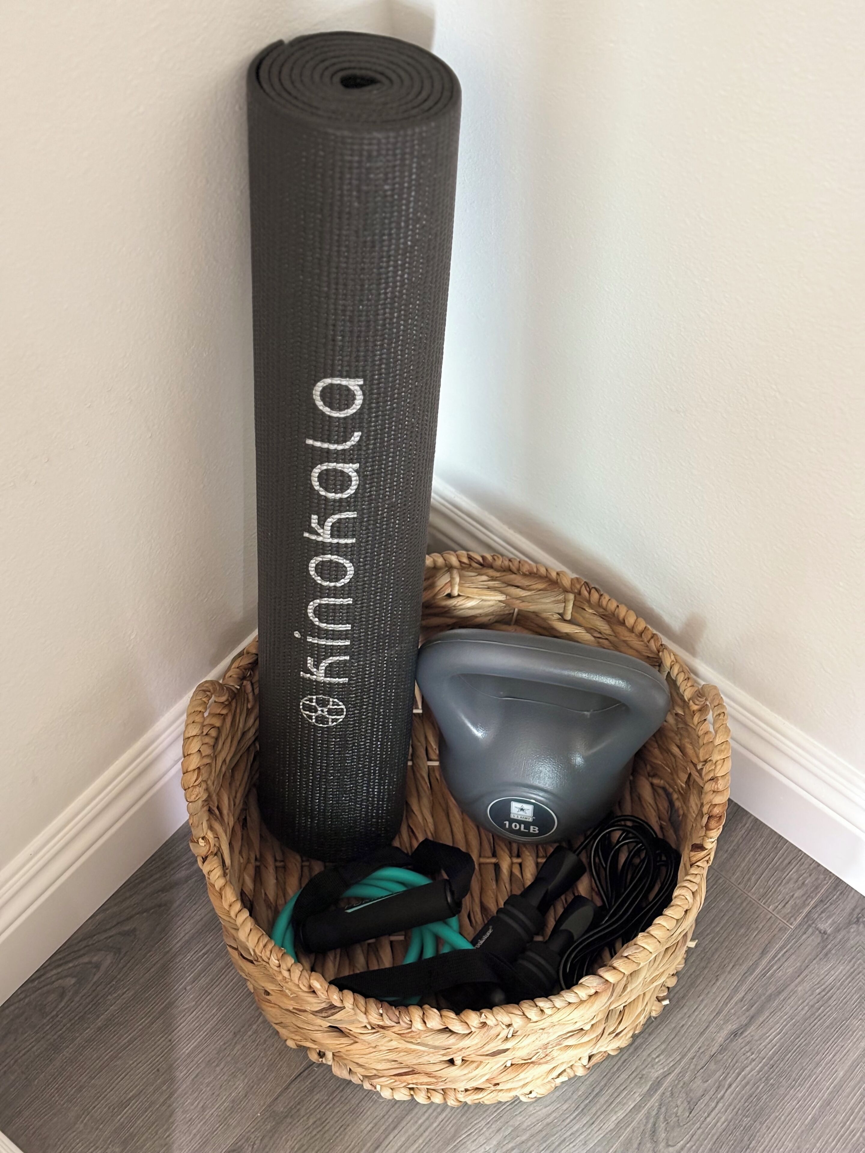 A woven basket containing a yoga mat, a water bottle, and resistance bands.