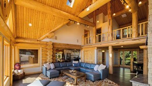 A spacious living area with a large L-shaped sectional sofa, a wooden ceiling, and a view of the kitchen. - Enchanting Morrison Home with Views and Wifi (Morrison)