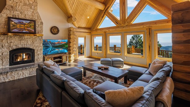 A spacious living room with a stone fireplace, large windows offering scenic views, and a cozy seating area. - Enchanting Morrison Home with Views and Wifi (Morrison)