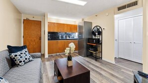 A compact living space with a kitchenette, a sofa with patterned cushions, and a coffee table with a vase.