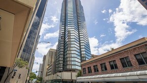 A tall, modern skyscraper with a curved glass facade, surrounded by other buildings.