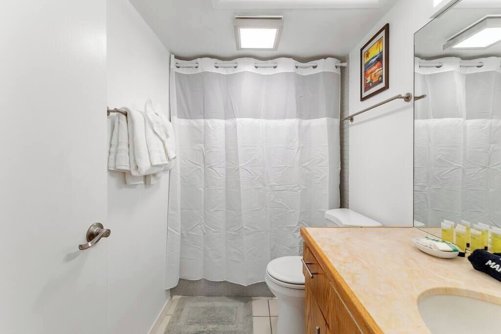 Un bagno con il water, il lavandino e una tenda doccia.