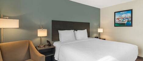 A hotel room with a large bed, two bedside tables, a chair, and a painting on the wall.