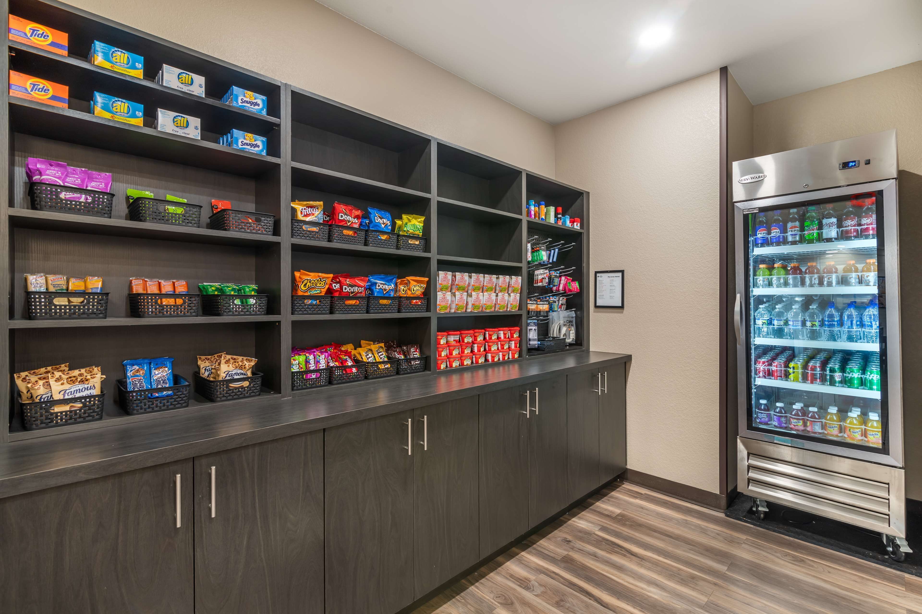 A vending machine stocked with various beverages and snacks, surrounded by shelves with packaged goods.