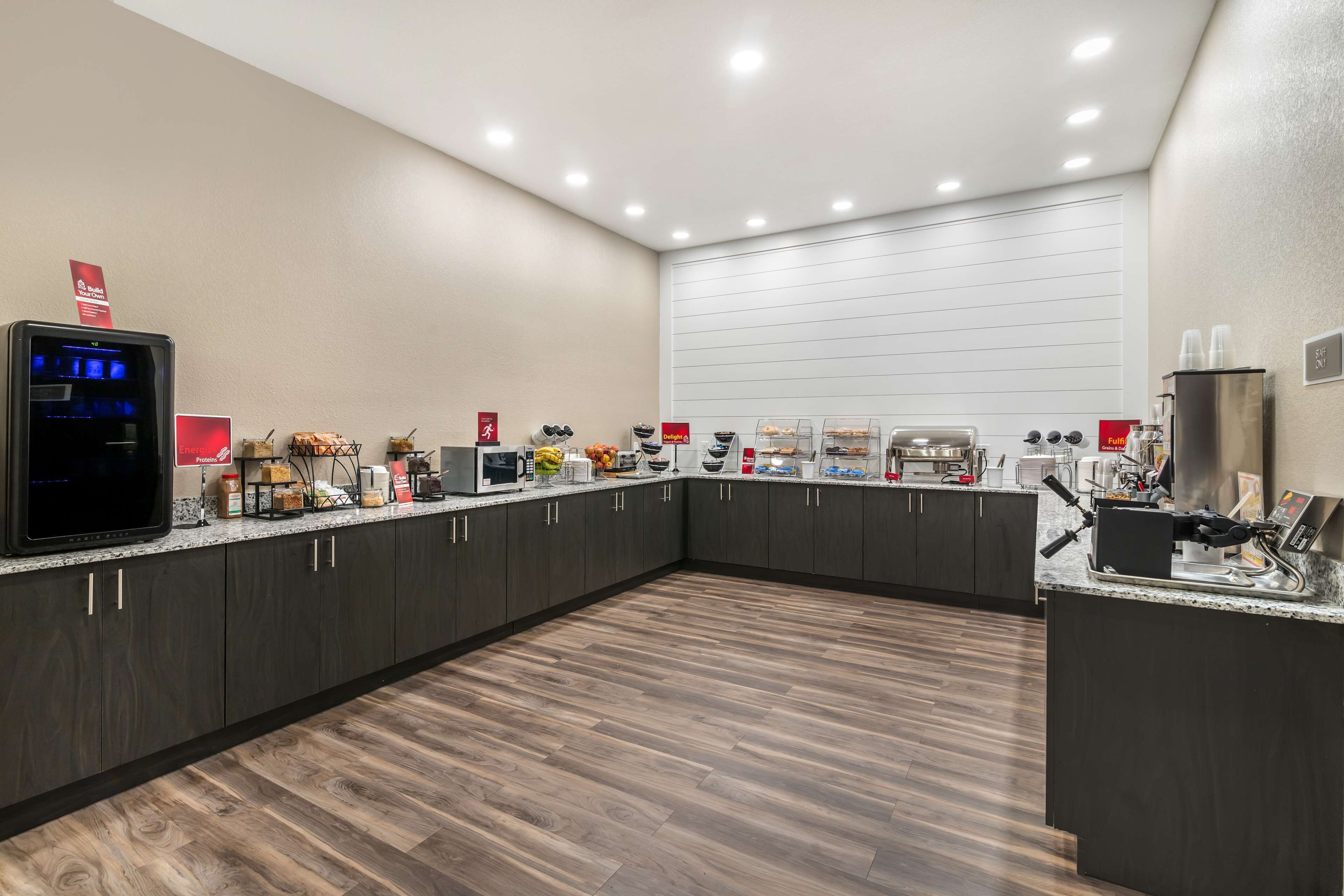 Una cocina moderna con armarios oscuros, encimera de granito y diversos electrodomésticos, incluyendo una cafetera y un microondas.