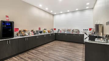 Una cocina moderna con armarios oscuros, encimera de granito y diversos electrodomésticos, incluyendo una cafetera y un microondas.