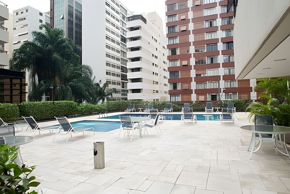 A rooftop pool area with lounge chairs and a pool.