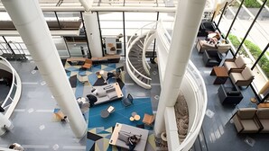 A modern atrium with a central seating area, a spiral staircase, and a view of the outdoors.