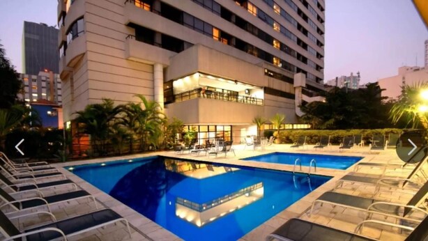A hotel with a pool area, including two pools and lounge chairs.