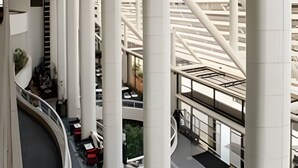 A modern building with multiple floors, large white columns, and a central atrium with a geometric floor design.