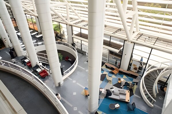 A modern interior with a central atrium, multiple levels, and a variety of seating areas.