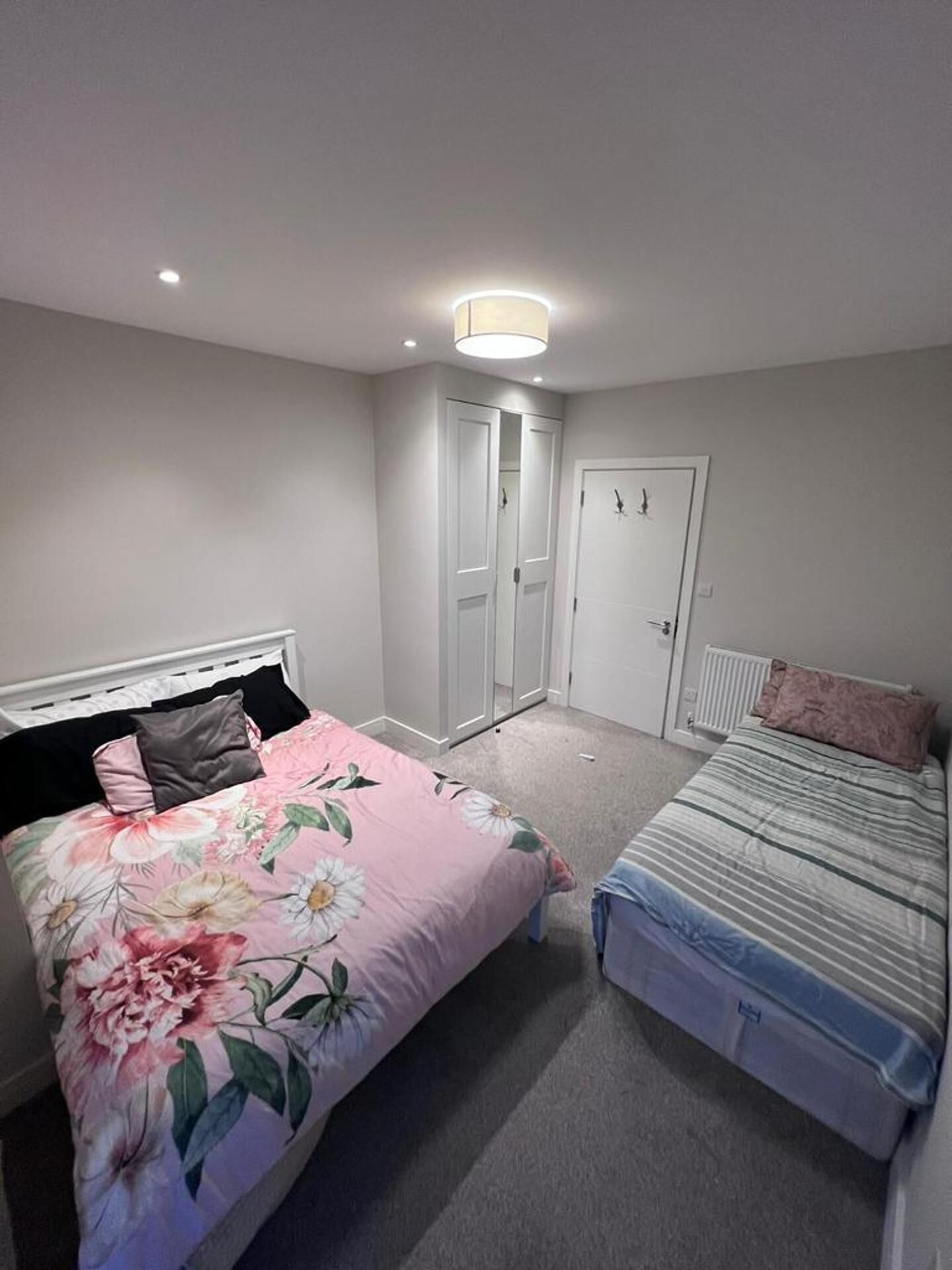 Een slaapkamer met twee bedden, een kast en een deur.