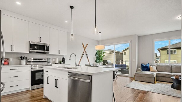 A modern kitchen with white cabinets, stainless steel appliances, and a central island. - Wanderer`s Haven | Private Nordic Spa | Game Room (Cochrane)