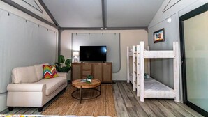 A compact living space with a sofa, a TV, a bunk bed, and a small coffee table.
