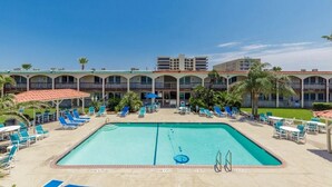 A hotel with a swimming pool, sun loungers, and a covered seating area. - Beach Access Across the Street, Shared Heated Pool (Corpus Christi)