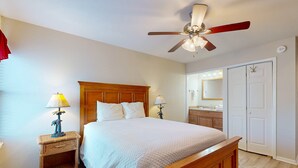 A bedroom with a wooden bed, two bedside tables with lamps, a ceiling fan, and a white wardrobe. - Beach Access Across the Street, Shared Heated Pool (Corpus Christi)