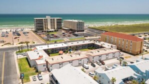 An aerial view of a hotel complex with multiple buildings, parking areas, and a beachfront. - Beach Access Across the Street, Shared Heated Pool (Corpus Christi)