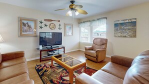 A living room with a television, leather sofas, a coffee table, and a ceiling fan. - Beach Access Across the Street, Shared Heated Pool (Corpus Christi)