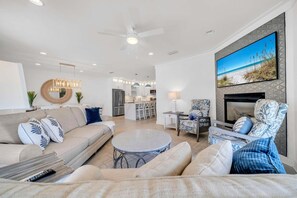Una sala de estar moderna con un sofá, sillones, una mesa de centro y un televisor montado en la pared.