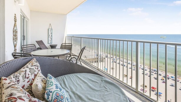 Un balcón con mobiliario de mimbre, una mesa y vistas a la playa.
