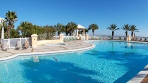 A swimming pool with a curved edge, surrounded by palm trees and lounge chairs. - Sea La Vie Martinique on the Gulf Sleeps 11 (Gulf Shores)
