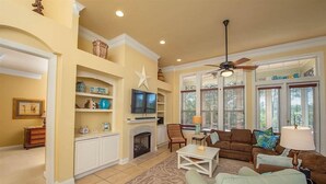A living room with a fireplace, television, and comfortable seating. - Sea La Vie Martinique on the Gulf Sleeps 11 (Gulf Shores)
