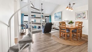A modern interior with a spiral staircase, a dining area with wooden furniture, and a view of the living room. - Cotton Bayou 2H 3BR With Loft (Orange Beach)