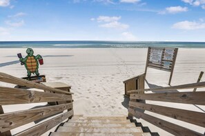 A beach with wooden stairs leading to a signboard.