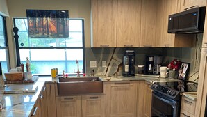 A modern kitchen with wooden cabinets, a black stove, and a coffee maker. - Rustic Elegance- Private Heated Salt pool, 2 bed, 2 bath, Fenced & Pet friendly (Port St Lucie)