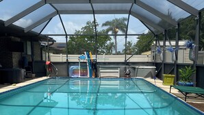 A swimming pool with a covered area, a slide, and a hot tub. - Rustic Elegance- Private Heated Salt pool, 2 bed, 2 bath, Fenced & Pet friendly (Port St Lucie)