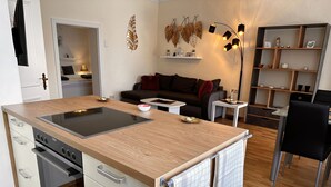 A modern kitchen with a central island, built-in oven, and a dining area with a table and chairs.