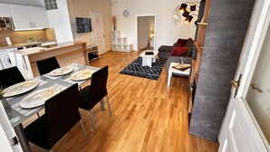 A modern apartment with a dining area, kitchen, living room, and a staircase leading to an upper floor.