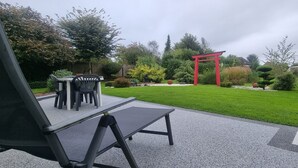 Un espace patio avec une table et des chaises, un portail torii rouge et une pelouse bien entretenue.