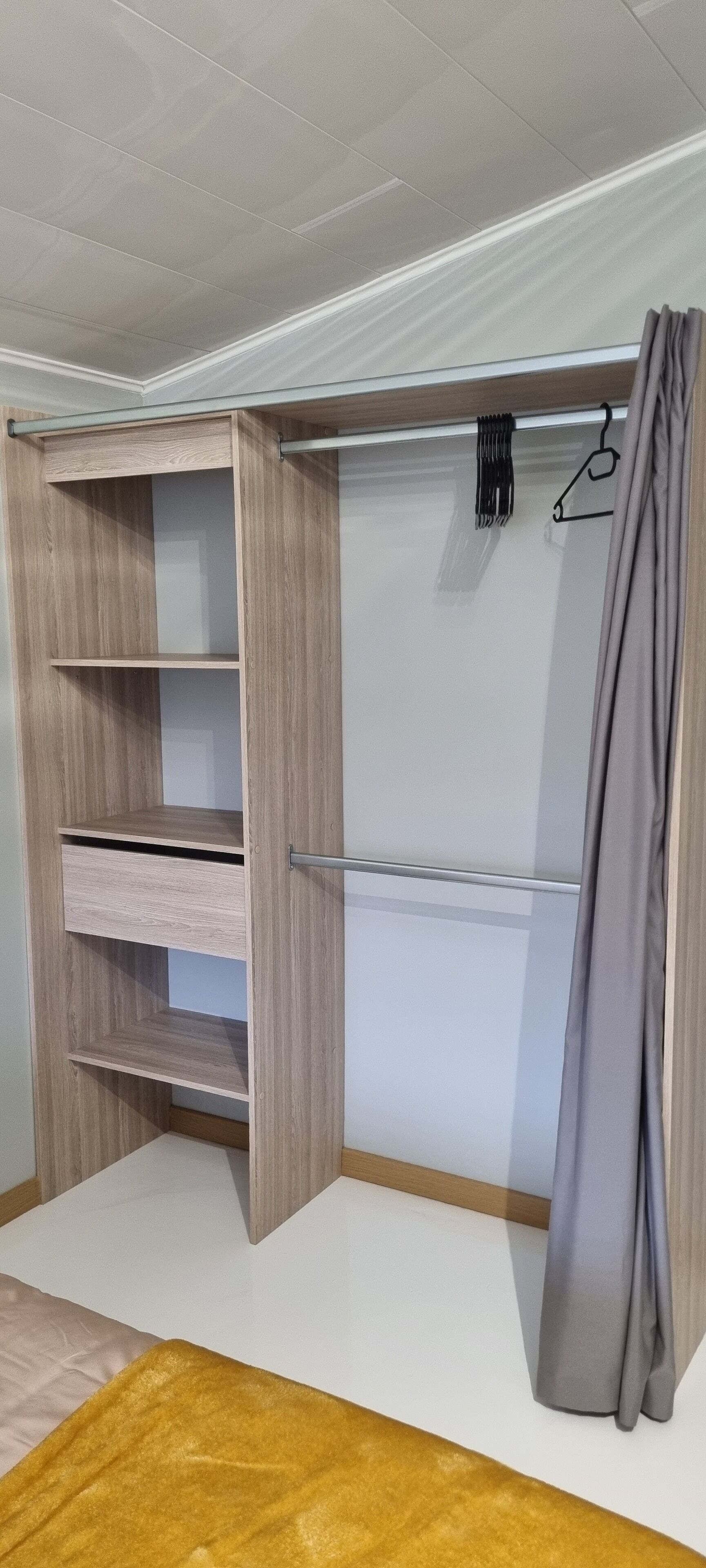 Un armario con repisas de madera y una cortina gris.