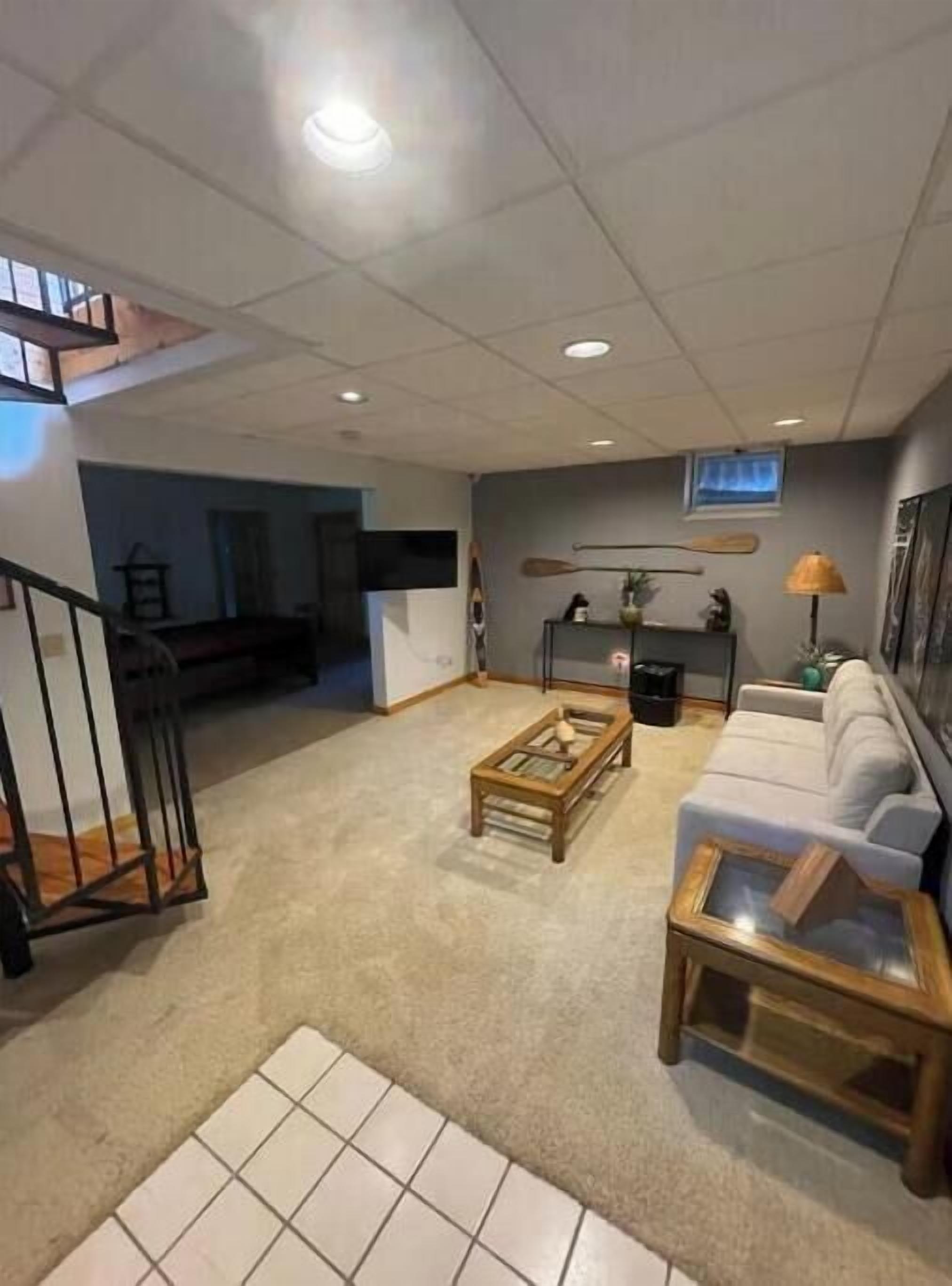 Ein geräumiges Wohnzimmer mit einer Couch, einem Couchtisch und einem an der Wand montierten Fernseher.