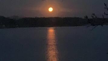 Een rustig wateroppervlak spiegelt een volle maan.