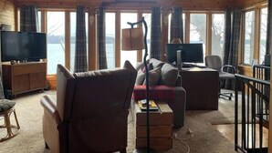 A cozy cabin with a large window, a television, a desk with a computer, and comfortable seating. - German lake Family Adventures

 (Waterville)
