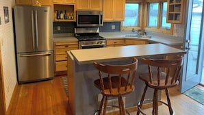 A modern kitchen with wooden cabinets, stainless steel appliances, and a large island with bar stools. - German lake Family Adventures

 (Waterville)