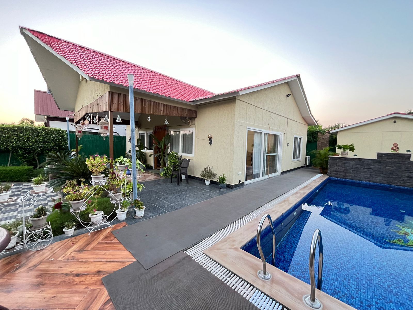A modern house with a swimming pool, potted plants, and a patio area.