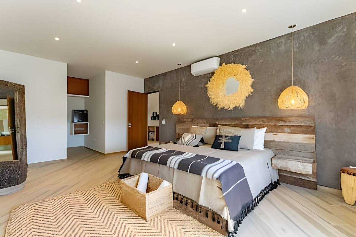 A modern bedroom with a large bed, wooden headboard, and pendant lights.