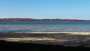 A beach with a clear view of a forested island across the water.