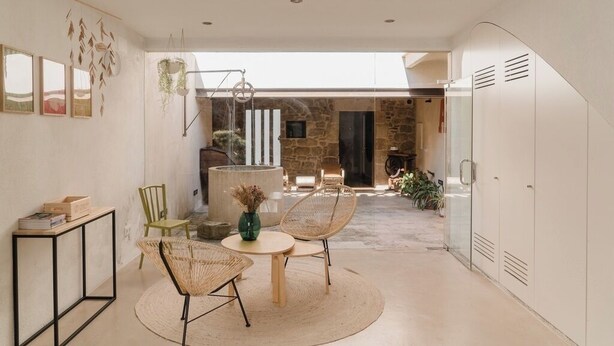 A modern interior with a dining area, a stone wall, and a view to an outdoor space. - Olivera, house in Rupià (Rupià)