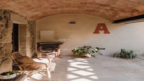 An arched stone ceiling, a wooden chair, a table, a potted plant, and a large letter 'A' on the wall. - Olivera, house in Rupià (Rupià)