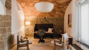 A cozy living room with a stone wall, a wooden bench, a sofa, and a hanging light fixture. - Olivera, house in Rupià (Rupià)