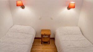 Allotjament petit d'una sola habitació amb dos llits individuals, una tauleta de nit de fusta i dues làmpades penjades a la paret.